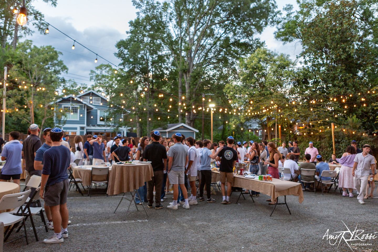 The Fleishman House backyard full of students at Shabbat tables under string lights