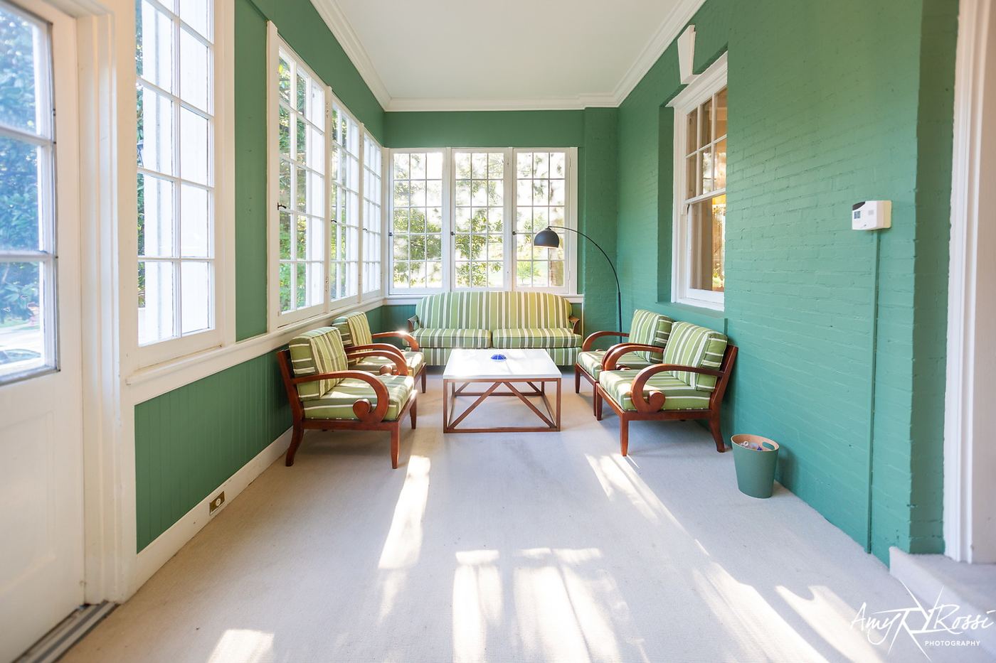 The green sunroom with seating and tall windows